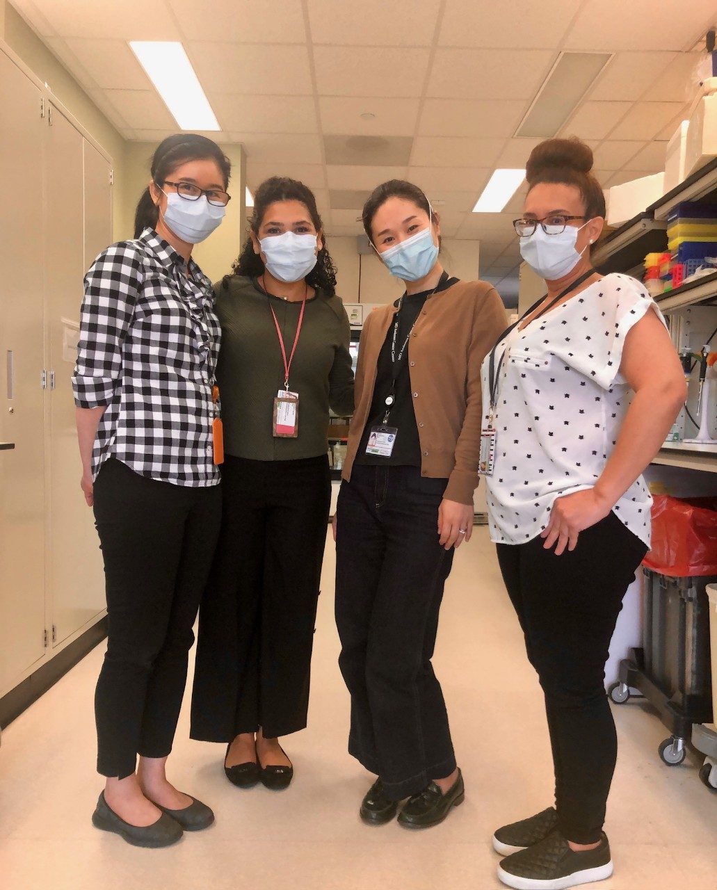 Four people wearing masks lined up for a group photo