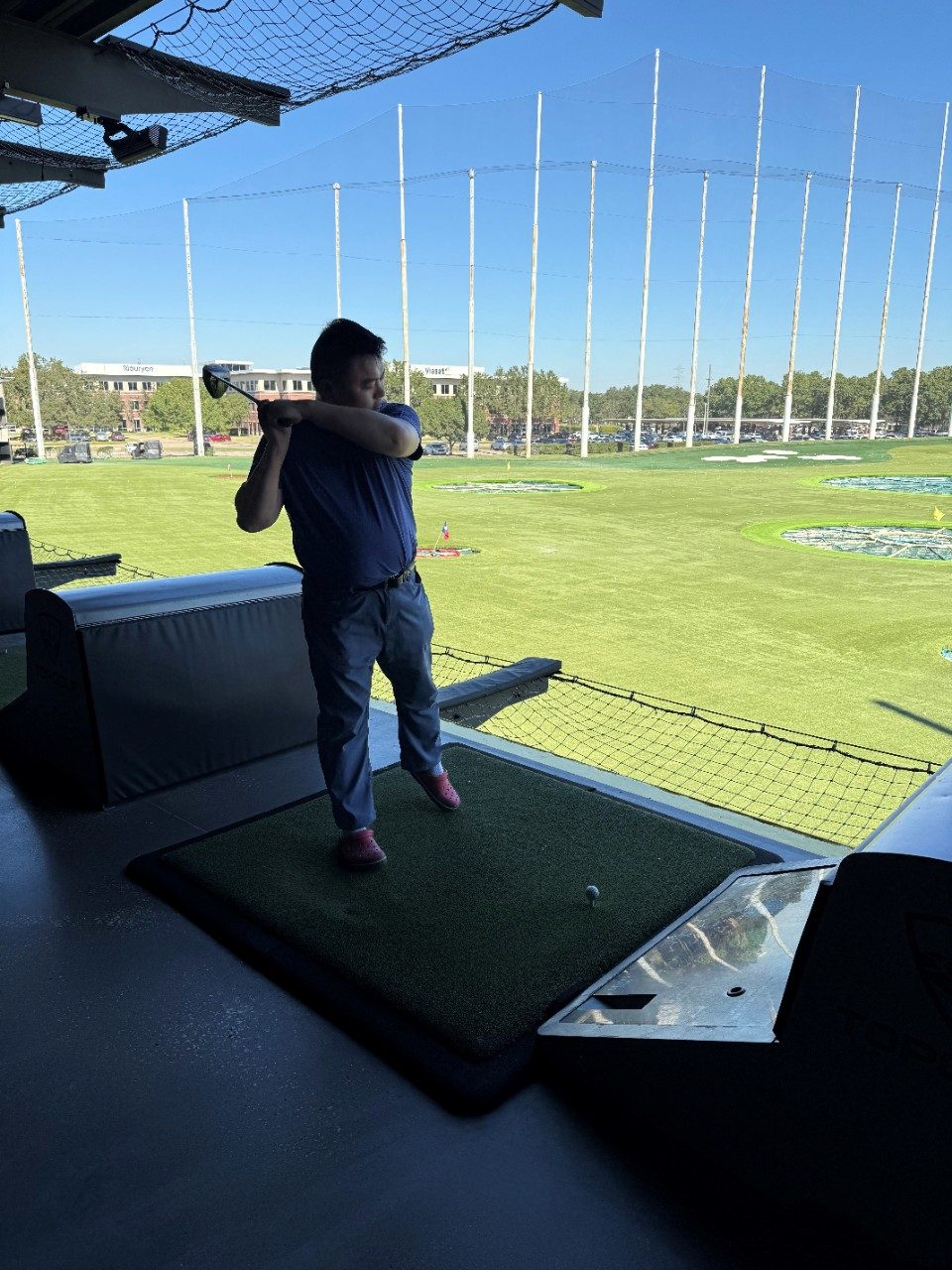 Person standing in the shade post-swing at TopGolf