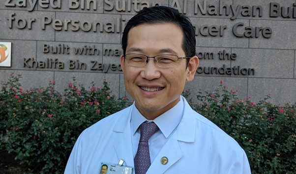 Dr. Lin wears a white coat and smiles outside of the Zayed building