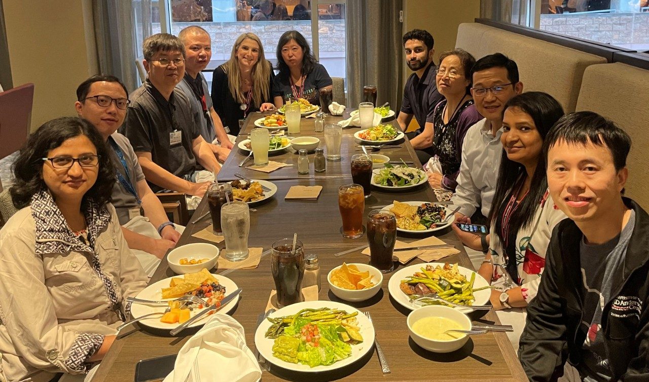 11 people sit around a table with food