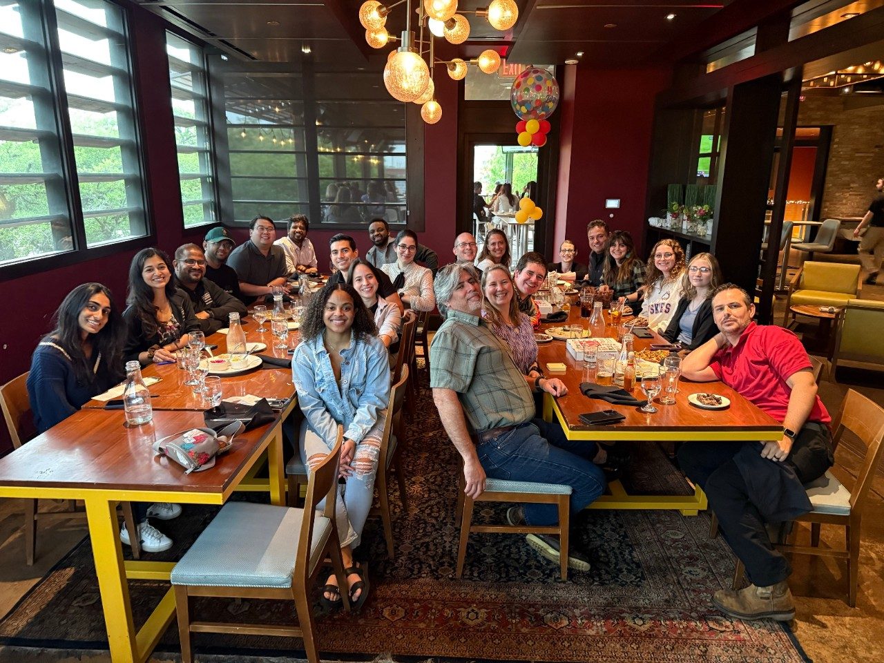 A large group of people seated at two long, rectangular tables at a restaurant