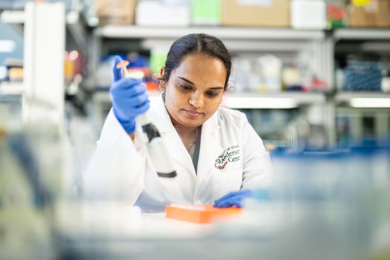 Lab member pipetting at a bench in lab