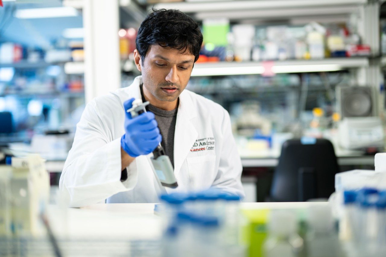 Lab member pipetting at a bench in lab