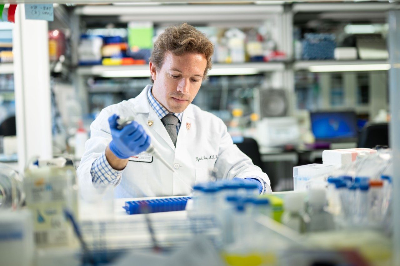 Lab member pipetting at a bench in lab