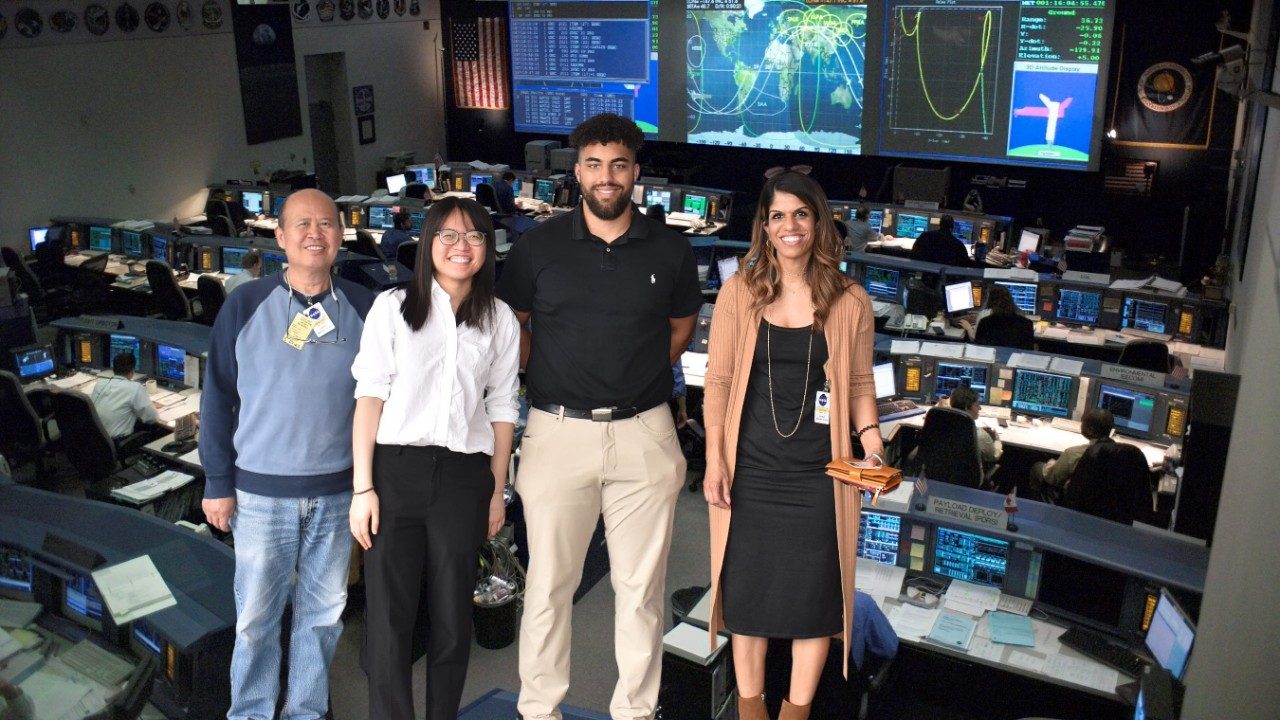 four people in front of mission control room