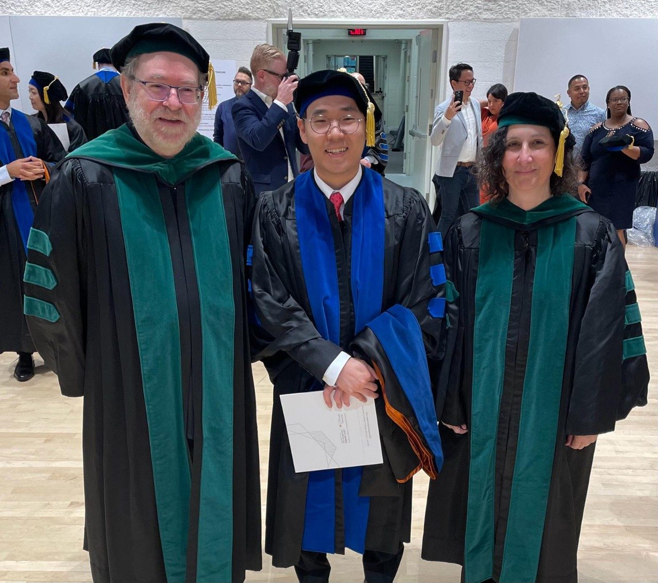 Drs. Fueyo and Gomez-Manzano posing with a trainee in academic robes