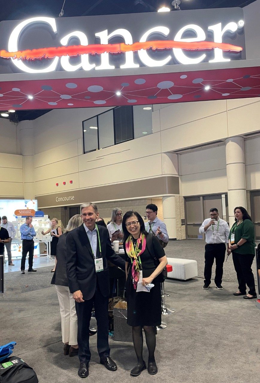 two people pose at a trade show booth
