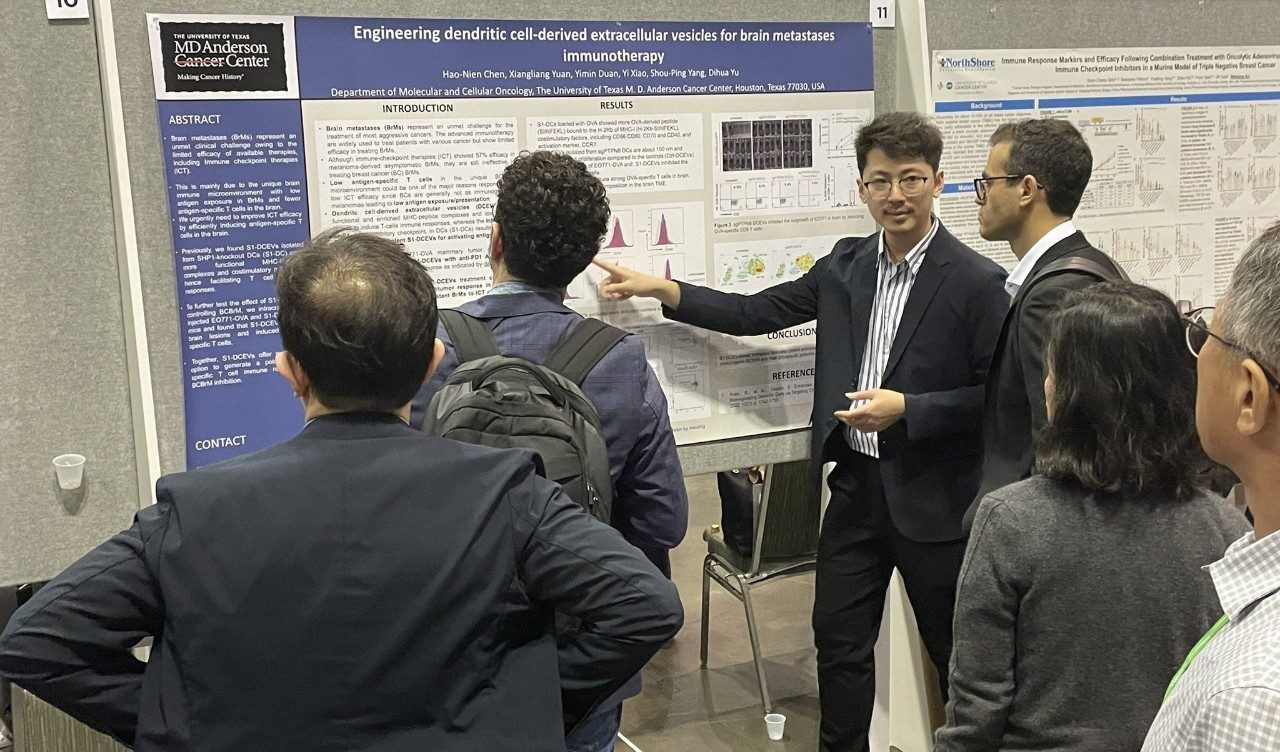 one man pointing at a poster while others look on