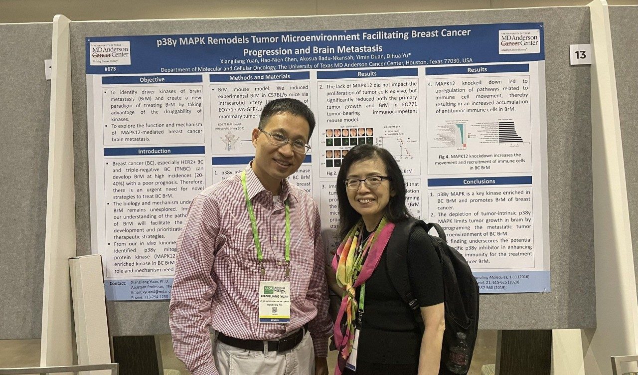 Two people pose by a scientific poster