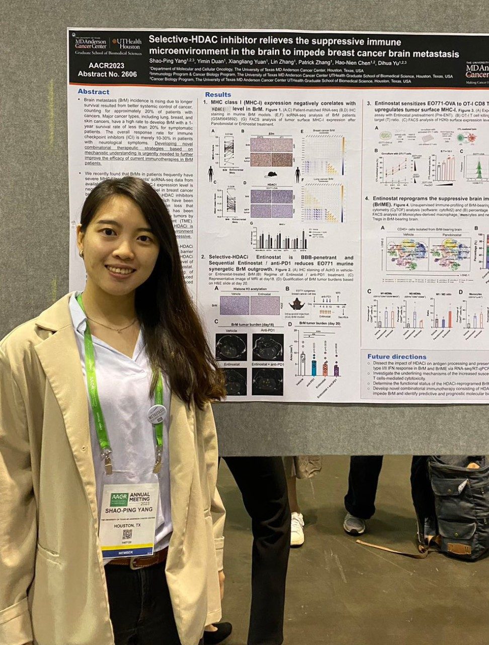 A woman stands next to a scientific poster