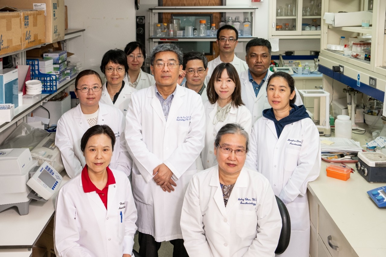 Ten people in lab coats standing in a lab