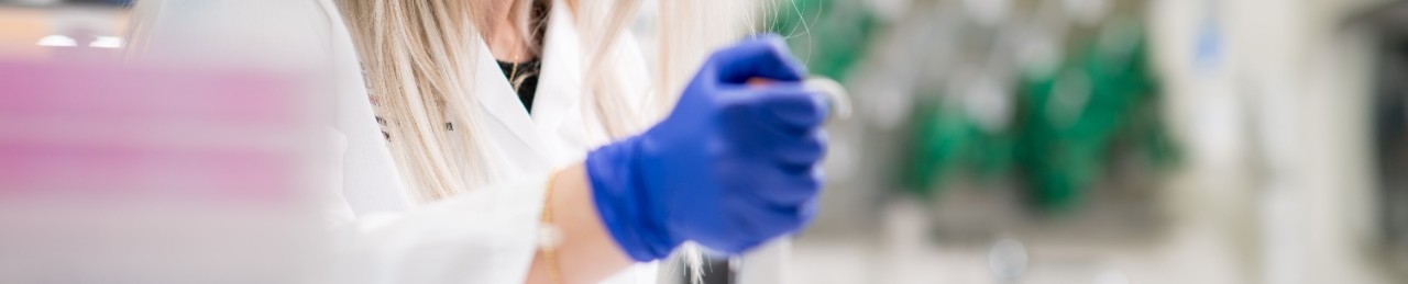 Gloved hand holding a pipette in a lab
